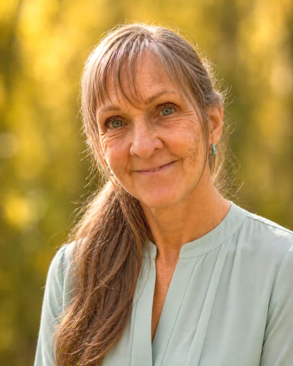 Feather Jones herbalist portrait outdoors with greenery background