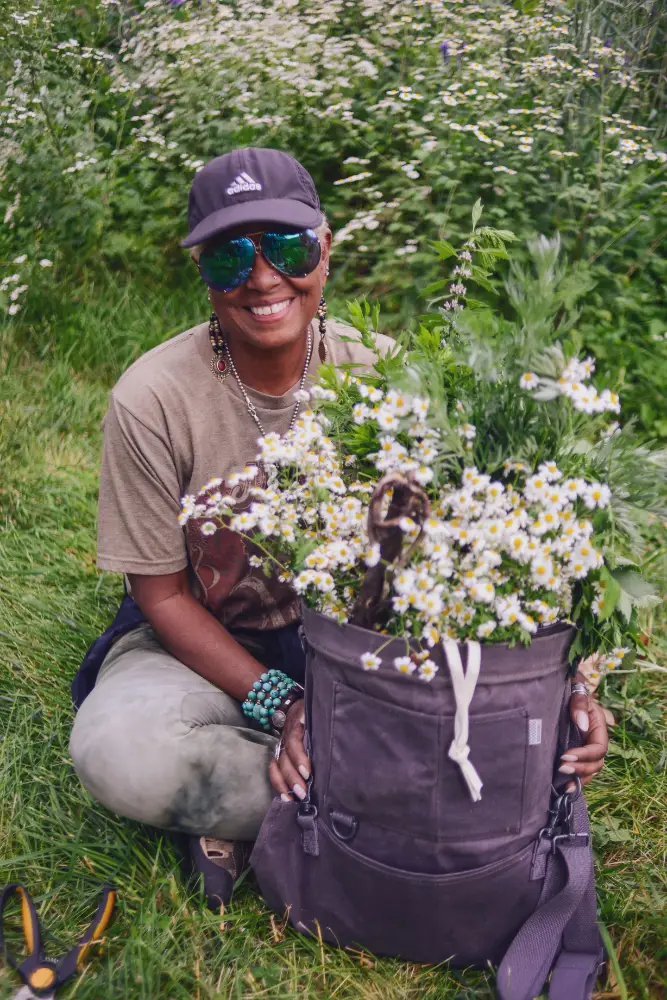 Student sitting in a field with a bag of freshly picked flowers