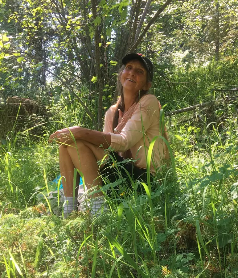 Feather Jones seated in sunlit grass outdoors